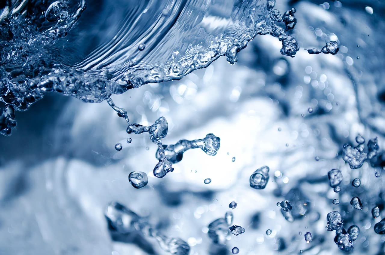Water droplets suspended in the air above a bright surface