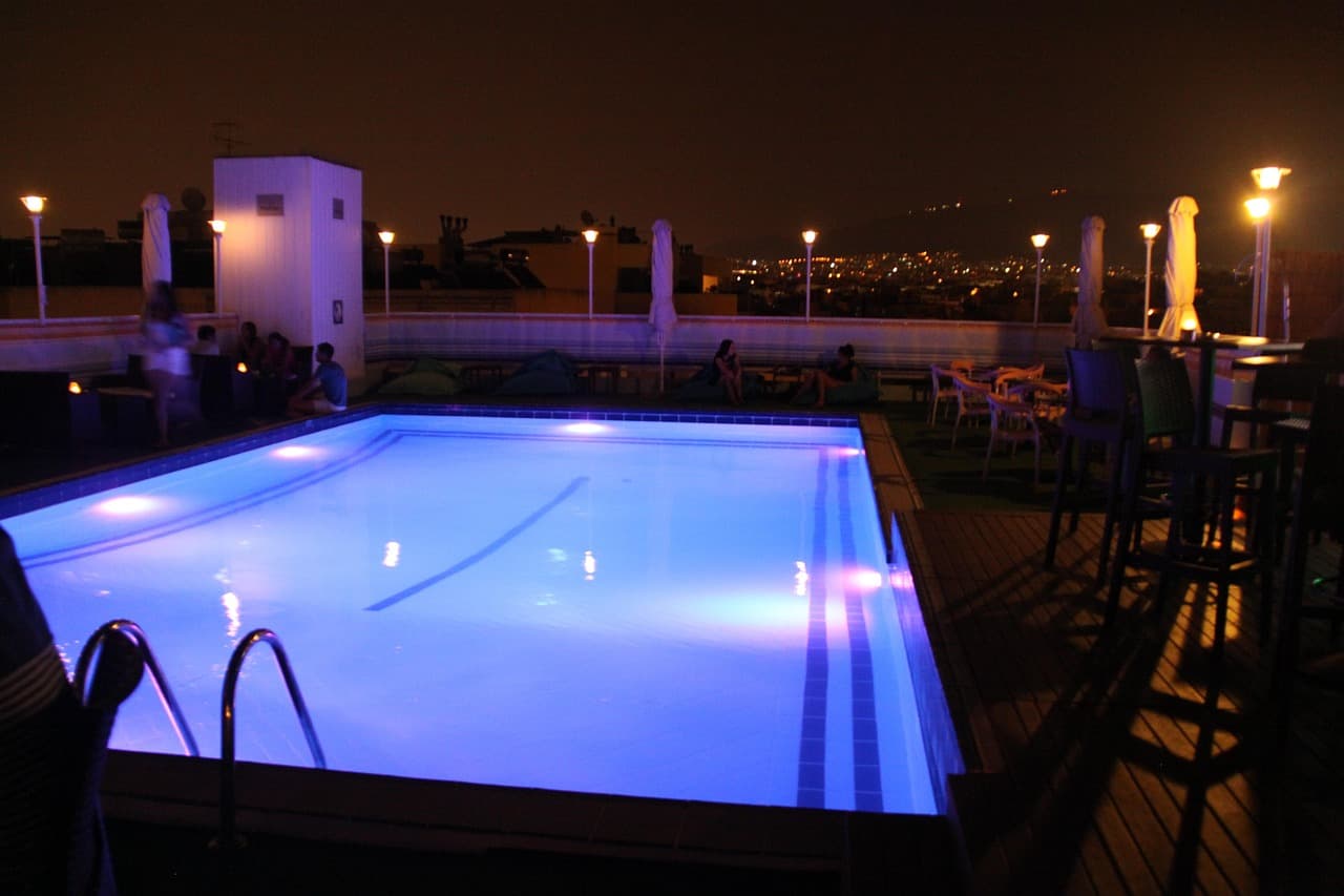 A pool lit from within at night, water glowing blue against dark decking