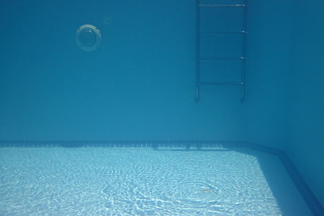 A drained pool shell showing tiled walls, floor drains and the finished coping line